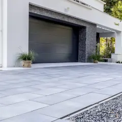 Nowoczesny podjazd z szarej kostki brukowej przed domem z garażem.