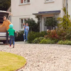 Rodzina rozładowuje samochód z kartonami przed domem z podjazdem z kruszywa.