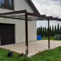 Nowoczesne zadaszenie tarasu z przezroczystym dachem, przyścienne, z brązową konstrukcją.